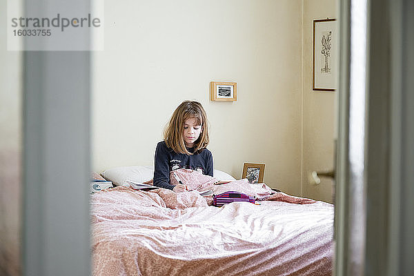 Mädchen sitzt auf ihrem Bett in ihrem Zimmer  lernt  Hausunterricht mit Laptop und Notebook