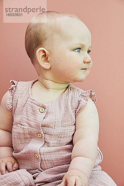 Porträt eines kleinen Mädchens auf rosa Hintergrund.