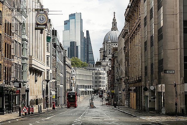 Blick entlang der leeren Fleet Street mit Bürogebäuden und der St. Paul's Cathedral zwischen modernen Hochhäusern in London während der Corona-Virus-Krise.