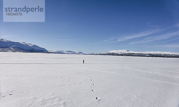 Fernansicht eines Jungen  der auf einem zugefrorenen See in Vasterbottens Lan  Schweden  spazieren geht.