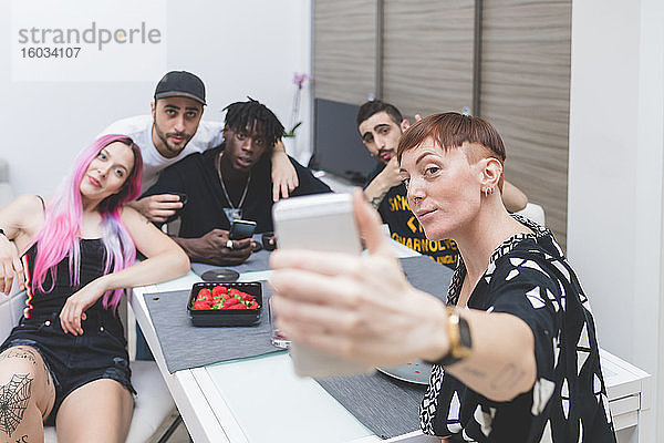 Gruppe junger Freunde  die am Tisch sitzen und ein Selfie machen.