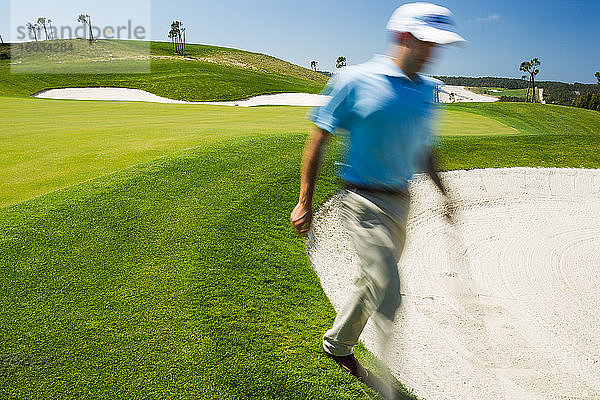 Männlicher Golfer läuft in Sandbunker.