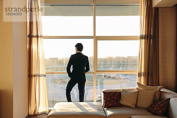Geschäftsmann schaut aus dem Schlafzimmerfenster eines Hotels