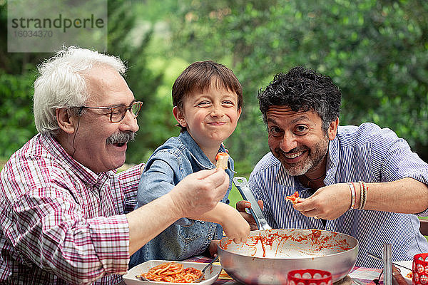 Junge genießt gemeinsam mit Vater und Großvater eine Mahlzeit