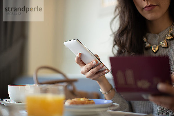 Geschnittene Aufnahme einer jungen Frau mit digitalem Tablett beim elektronischen Einchecken während des Frühstücks in einem Boutique-Hotel in Italien