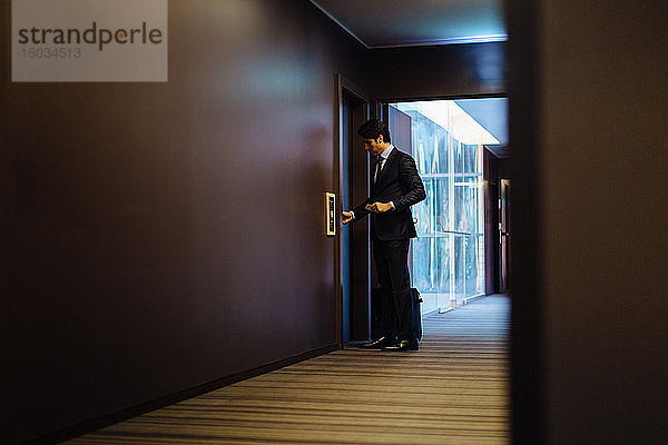 Geschäftsmann mit Rollgepäck betritt Hotelzimmer