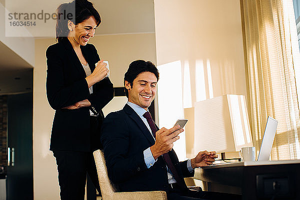 Geschäftsmann und Geschäftsfrau tauschen Textnachrichten im Hotelzimmer aus