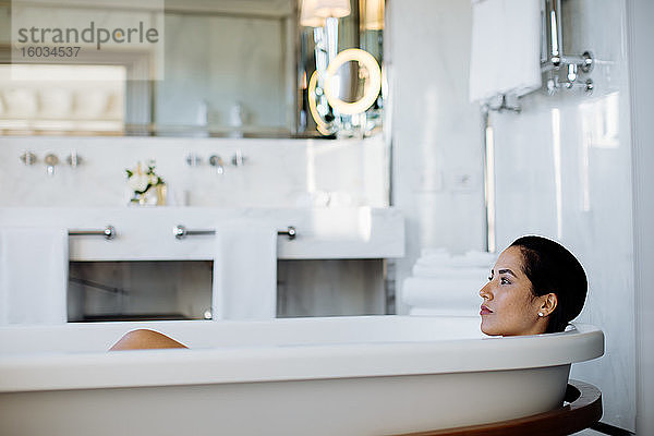 Frau entspannt sich in Badewanne in Suite