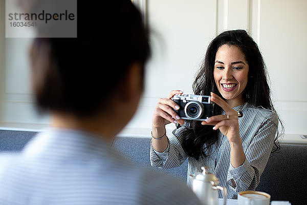 Junge Frau fotografiert Freundin beim Frühstück im Boutique-Hotel in Italien