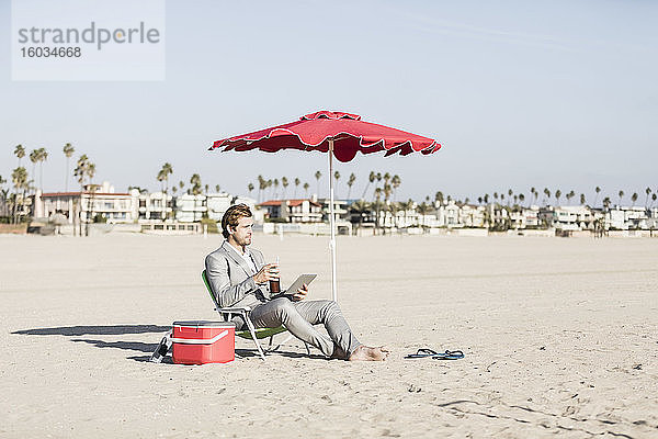 Geschäftsmann mit digitalem Tablet arbeitet am sonnigen Strand  Los Angeles  Kalifornien