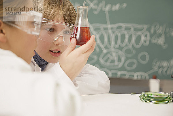 Schüler der Junior-Highschool untersuchen Becher mit Flüssigkeit im naturwissenschaftlichen Unterricht