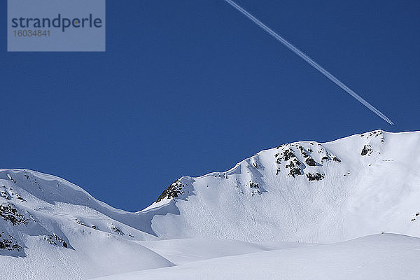 Flugzeugkondensstreifen bei strahlend blauem Himmel über verschneitem Berg  Davos  Kanton Graubünden  Schweiz