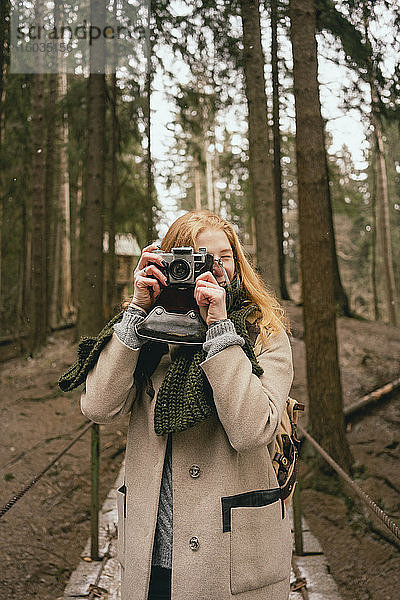 Porträt einer Frau mit Retro-Kamera in Wäldern