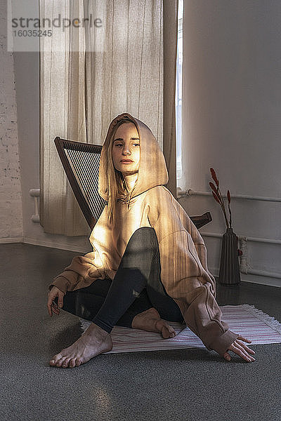 Porträt einer selbstbewussten jungen Frau mit Kapuzensweatshirt im Yoga-Studio