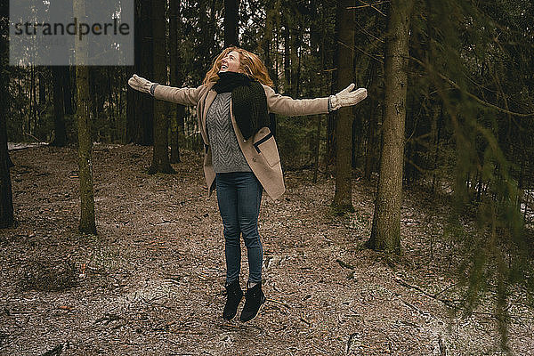 Unbekümmerte Frau springt vor Freude im Wald
