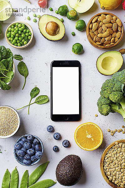 Gemüse  Obst  Linsen und Mandeln arrangiert um ein Smartphone