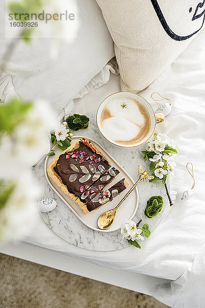 Osterfrühstück im Bett mit Schokoladenkuchen und Kaffee