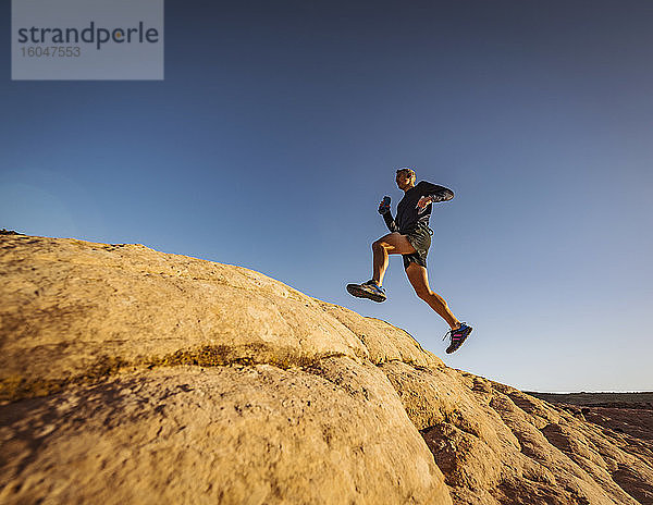 USA  Utah  St. George  Mann springt beim Laufen in felsiger Landschaft