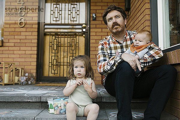 Vater mit Kindern auf der Veranda sitzend