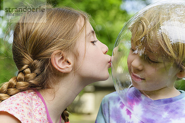 Mädchen küsst Jungen mit Blase zur sozialen Distanz
