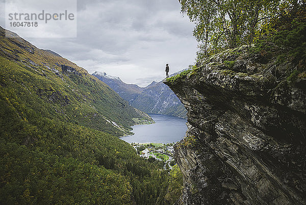 Norwegen  Geiranger  Mann steht am Rand einer Steilklippe über dem Geirangerfjord