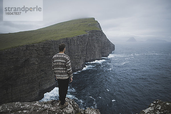 Dänemark  Färöer-Inseln  Sorvagur  Mann schaut auf Meeresküste mit Klippen