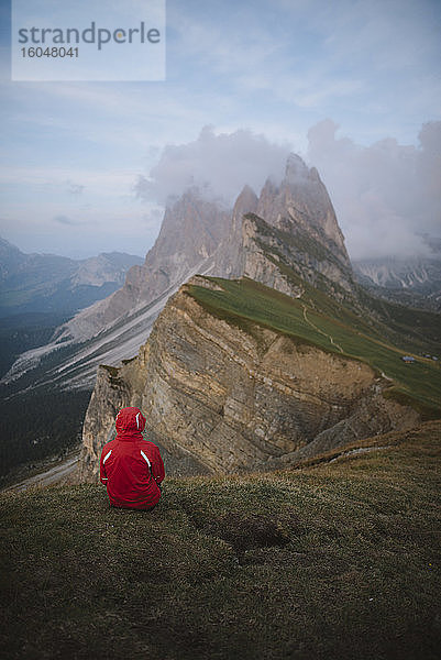 Italien  Dolomiten  Berg Seceda  Person sitzt auf Gras und schaut auf den Berg Seceda in den Dolomiten