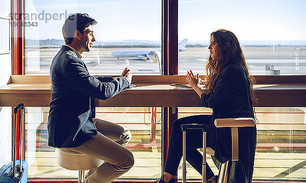 Geschäftsleute unterhalten sich in einem Flughafencafé
