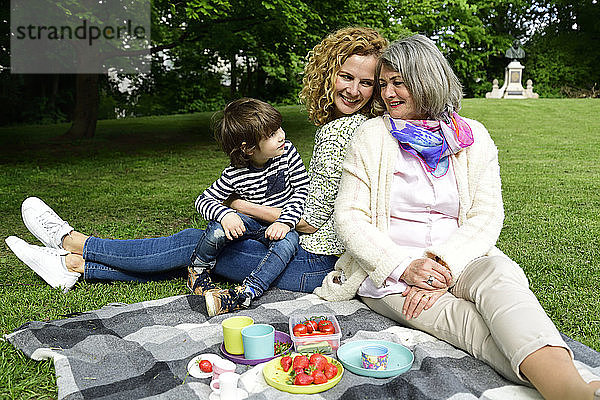 Glücklicher Junge genießt Picknick mit Mutter und Großmutter im öffentlichen Park