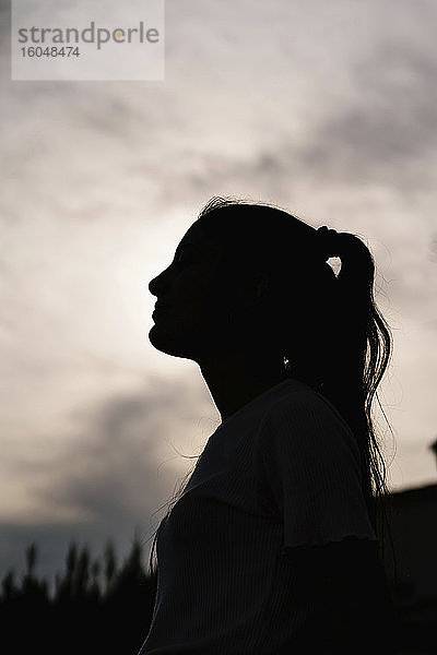 Silhouette einer Frau mit Pferdeschwanz gegen den Himmel bei Sonnenuntergang