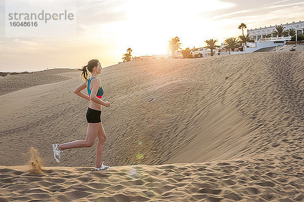 Frau  die bei Sonnenaufgang durch die Dünen läuft  Gran Canaria  Spanien