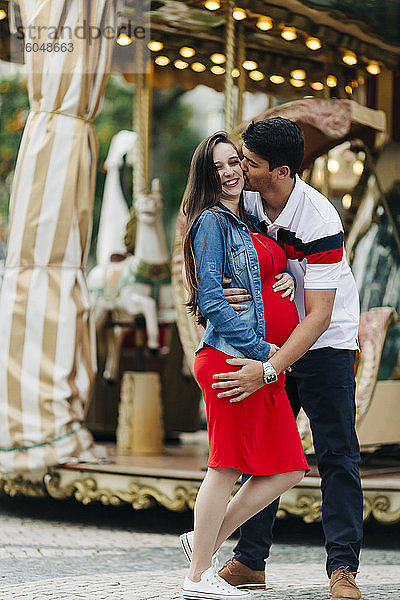 Glücklicher Mann küsst schwangere Frau vor einem Vergnügungspark  Cascais  Portugal