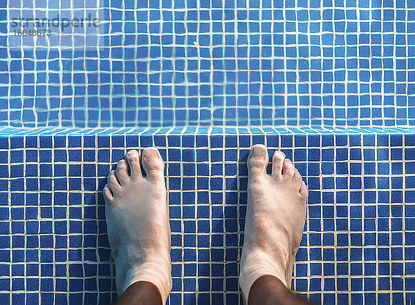 Füße eines Mannes  der knöcheltief im Schwimmbad steht