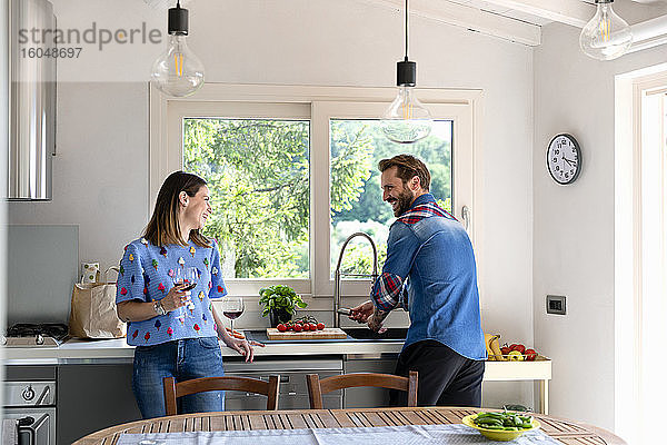 Lächelndes mittleres erwachsenes Paar im Gespräch in der Küche zu Hause