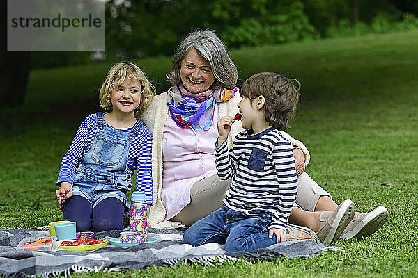 Glückliche Großmutter genießt Picknick mit Enkelkindern im Park