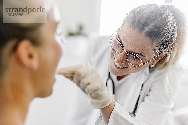Ärztin  die eine Patientin mit Zungenspatel untersucht
