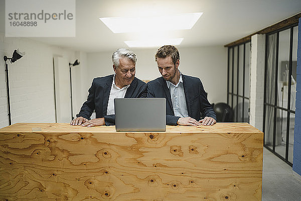 Zwei Geschäftsleute arbeiten am Tresen  schauen auf einen Laptop  lächeln