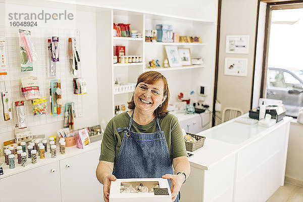 Lächelnde Bäckerin  die im Laden stehend eine Cupcake-Box ausliefert