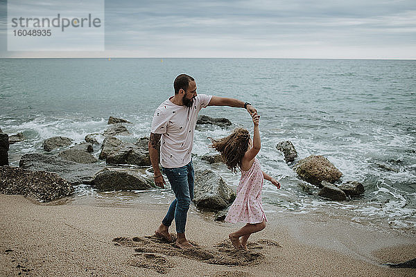 Tochter tanzt mit Vater am Strand