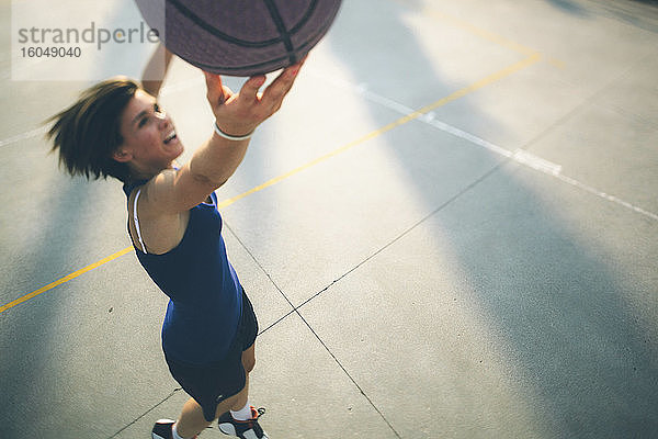 Teenager-Mädchen springt beim Üben von Basketball auf dem Platz
