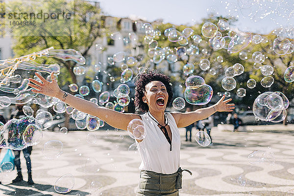 Unbekümmerte erwachsene Frau  die mit Seifenblasen spielt  während sie in der Stadt steht