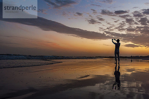 Mann  der ein Smartphone-Foto bei Sonnenuntergang am Meer macht  Gran Canaria  Spanien