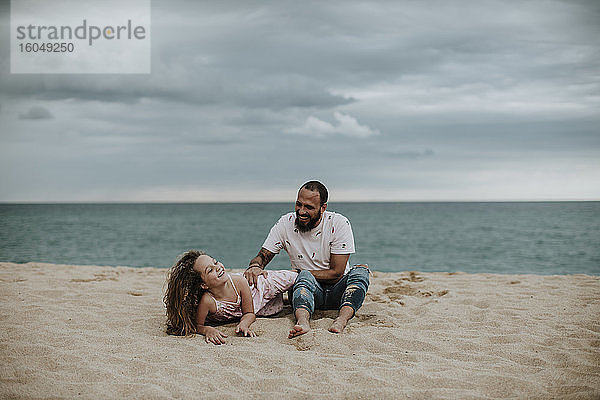 Vater spielt mit Tochter im Sand am Strand
