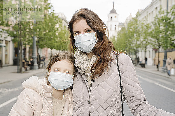 Mutter und Tochter mit Masken stehen auf der Straße in der Stadt