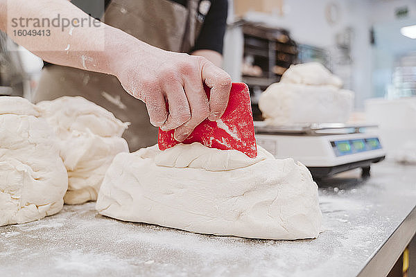 Bäckerin bei der Zubereitung eines Brotlaibs am Küchentisch in einer Bäckerei