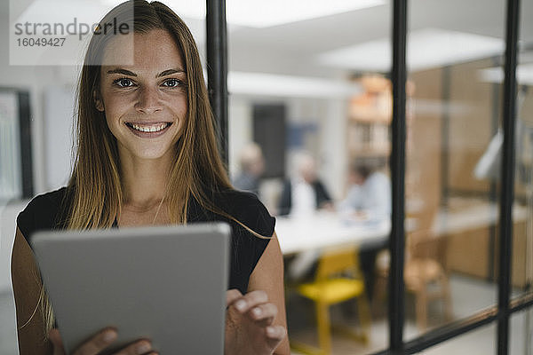 Junge Geschäftsfrau im Büro stehend  mit digitalem Tablet