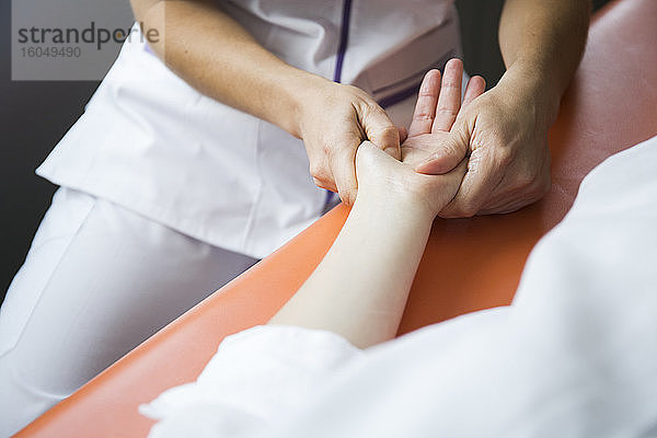 Die Hände einer Physiotherapeutin massieren die Hand einer Frau
