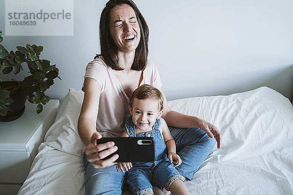 Mutter und kleines Mädchen machen ein Selfie mit Smartphone zu Hause