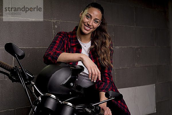 Junge lächelnde Frau auf einem Motorrad sitzend