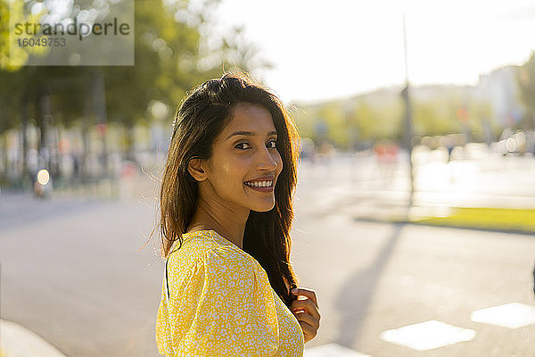 Schöne Frau lächelnd  während stehend auf Stadt Straße während sonnigen Tag